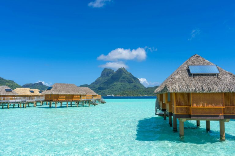 The water is crystal blue and clear and there are huts in the water